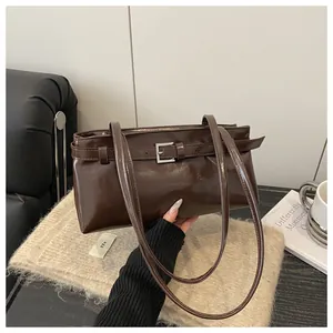 Détail d'un sac à bandoulière en cuir poli marron foncé avec boucle argentée décorative