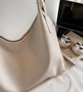 Detail of a beige large tote bag showing smooth matte leather and vertical stitching