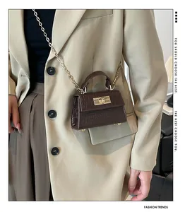 Detail of dark brown croc-effect mini bag with gold twist lock and chain strap