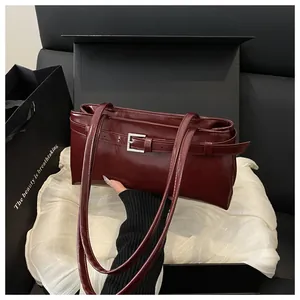 Détail du sac bandoulière en cuir bordeaux avec boucle argentée sur coffret cadeau