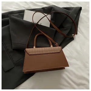 Dettaglio borsa a tracolla marrone a trapezio con patta intrecciata e fibbie oro