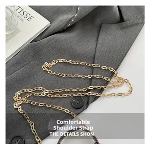 Detail of elegant gold chain strap on dark brown leather bag with grey suit jacket