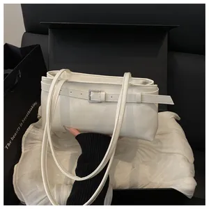 Détail d'un sac sous les bras en cuir blanc avec boucle argentée sur boîte cadeau