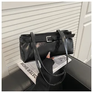 Détail du sac porté épaule en similicuir noir brillant avec boucle argentée et fines brides
