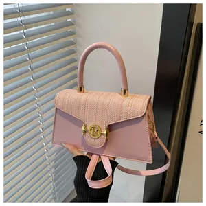 Dettaglio della borsa rosa in ecopelle con patta intrecciata e fibbia dorata logo M