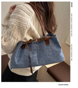Detail of blue leopard print tote bag with brown leather strap and golden buckle accent