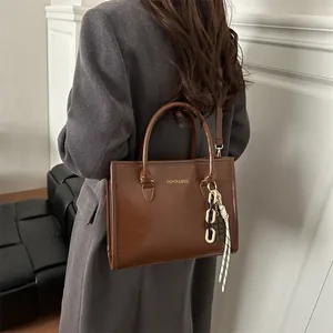 Grand sac à main marron en cuir avec lettrage doré et pendentif contrasté chic