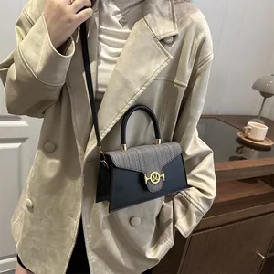 Borsa a tracolla a trapezio in tweed nero con fibbia dorata su un cappotto beige