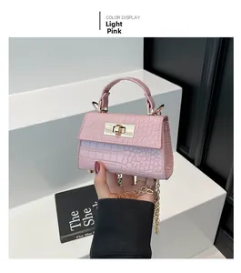 Close-up of light pink mini handbag featuring crocodile pattern and gold hardware