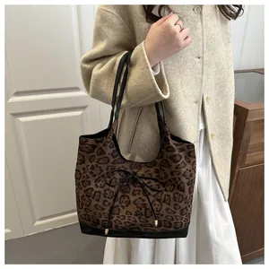 Detail of leopard print tote bag featuring black leather base and bow knot decoration