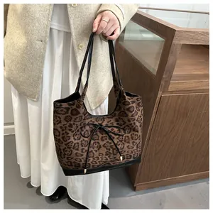 Detail of leopard print tote bag featuring a leather trim and a front bow decoration