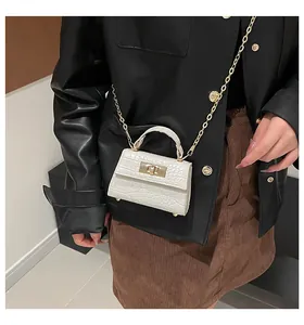 Mini white crocodile texture handbag with gold clasp shown in lifestyle styling