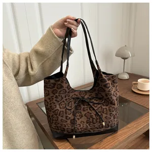 Close-up of leopard print tote bag featuring black drawstring bow and suede texture
