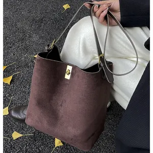 Retro dark brown large bucket bag with gold metal lock and leather straps on autumn street