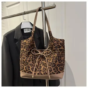 Detailed view of leopard print tote bag with bow drawstring and gold metal accents
