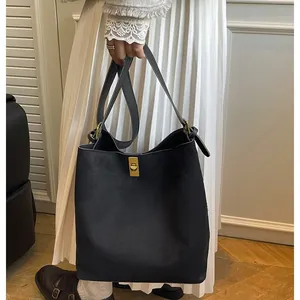 Large black vintage bucket bag with gold clasp shown in a lifestyle shoulder carry pose