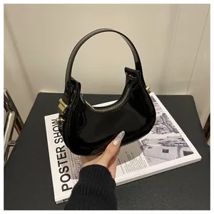 Gros plan du sac hobo en cuir verni noir avec fermeture éclair dorée sur un magazine