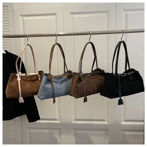 Detail view of large leopard print tote bags in four colors hanging on a metal rack