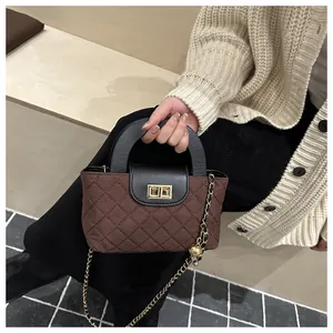 Detail of brown quilted handbag with gold hardware and chain strap on model