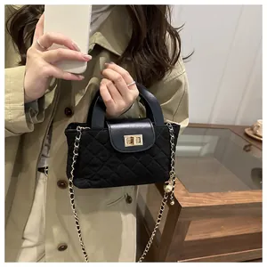 Close-up of black quilted handbag with gold metal twist-lock and chain strap detail