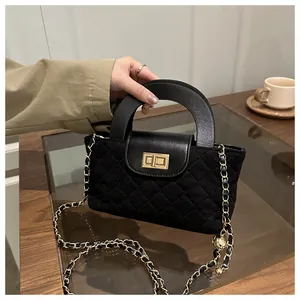 Detail of black quilted suede crossbody bag with gold lock and chain strap