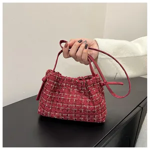 Detail of red tweed underarm bag with gold silk texture and leather shoulder strap