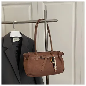 Detail of vintage brown suede tote bag featuring decorative buckle and wooden bead charms