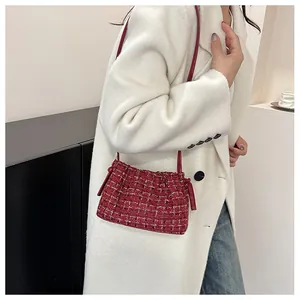 Close-up of red tweed shoulder bag with side knot details on a white coat