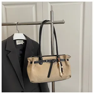 Detail of matte beige suede tote bag with black leather straps and wooden bead charm