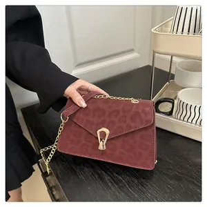 Detail of burgundy leopard print crossbody bag with gold chain and metal buckle