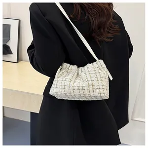 Detail of a beige tweed cloud bag with plaid pattern on a black blazer background