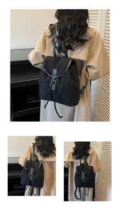 Detail of minimalist black suede backpack with flap closure, metal buckle and drawstring