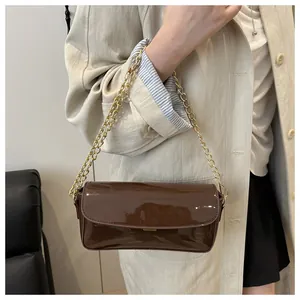 Detail view of glossy oil wax leather shoulder bag with golden chain and metal buckle
