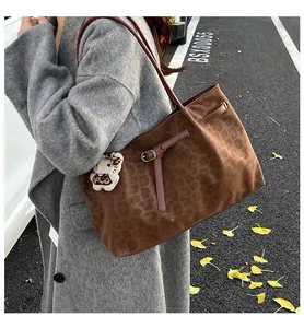 Dettaglio della borsa tote leopardata in pelle scamosciata con cinturini in cuoio