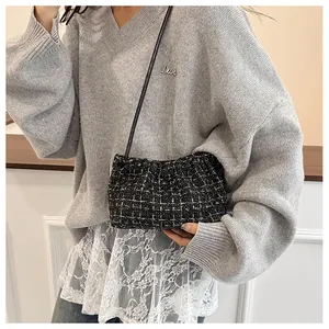 Detail of black tweed crossbody bag with gold metallic threads and pleated cloud design