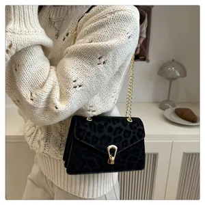 Detail of trendy leopard print crossbody bag with gold chain strap on a stylish model