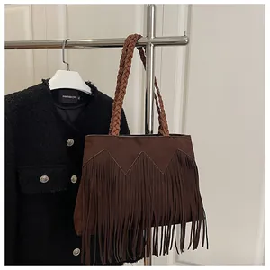 Détail du sac à bandoulière marron à franges avec sangle tressée et texture suédine