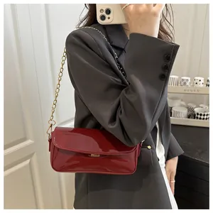 Detail of deep red oil wax leather baguette bag with elegant golden chain strap