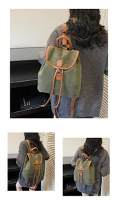 Detail of vintage dark green canvas backpack with brown leather trim and drawstring closure