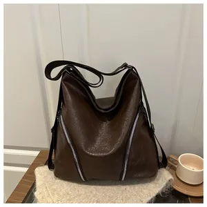 Dettaglio della borsa tote in pelle cerata marrone scuro con cerniere argentate