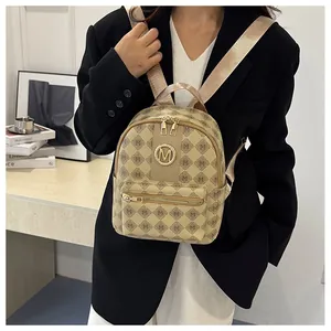 Detail of trendy beige letter printed backpack featuring a gold-tone M logo and zippers