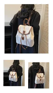 Close-up of vintage canvas backpack with brown leather trim shown on a black wool coat