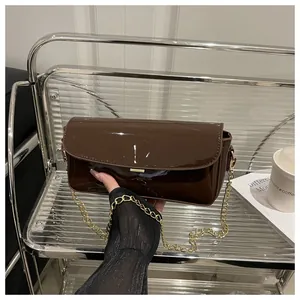 Detail of dark brown oil wax leather bag featuring a glossy finish and gold chain strap