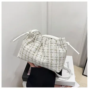 Close-up of beige tweed checkered underarm bag with drawstring design and leather strap