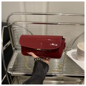 Detail view of dark red oil wax leather handbag with golden chain strap and mirror finish