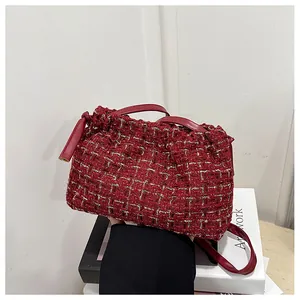 Detail of burgundy tweed shoulder bag featuring gold tinsel weave and leather strap