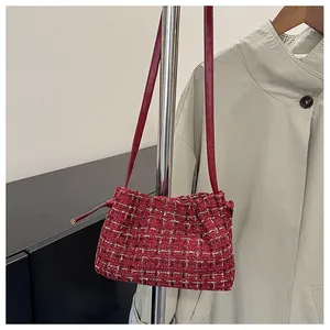 Detail of red tweed woven texture and slim leather strap on a chic shoulder bag