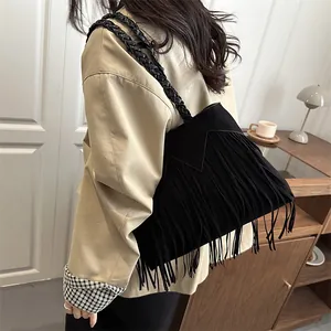 Sac cabas noir à franges de style bohème en daim avec bandoulière tressée portée par modèle