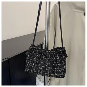 Detail of tweed drawstring shoulder bag with gold thread accents and leather strap