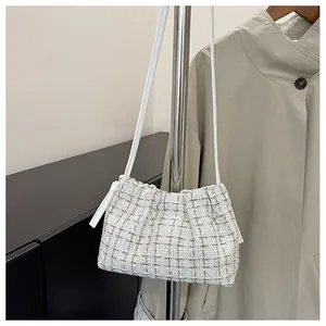Detailed macro view of white tweed shoulder bag with woven gold metallic texture